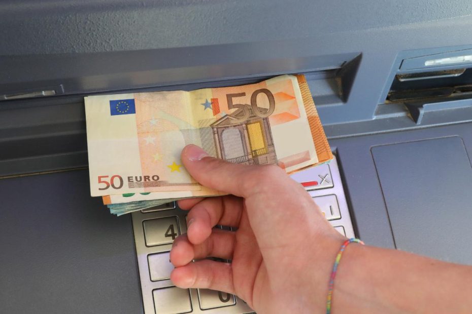 En man tar ut pengar från en bankomat.