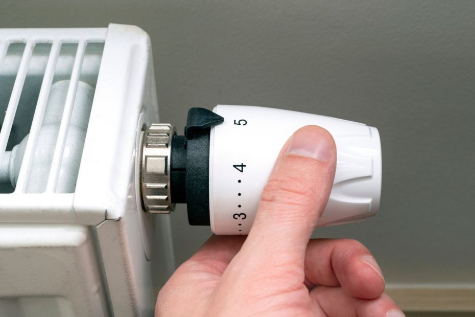 En person reglerar radiator med hjälp av en radiatorventil.