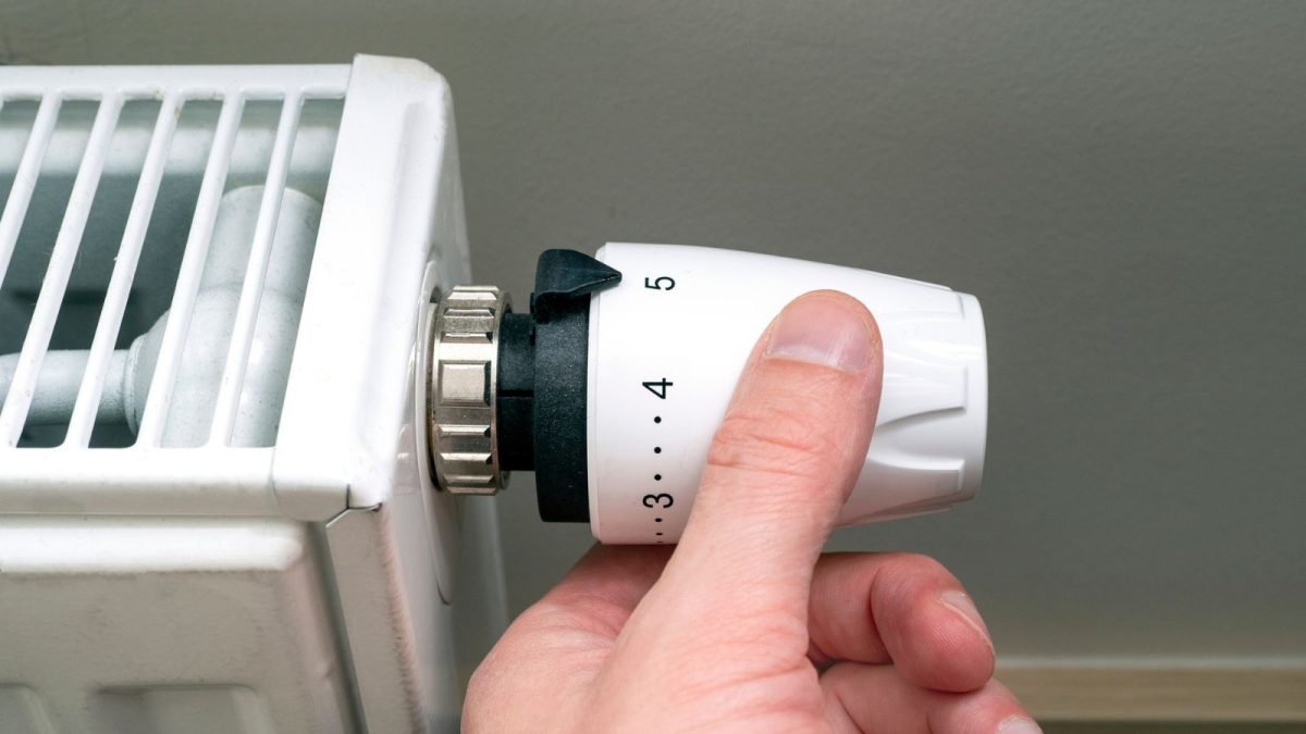 En person reglerar radiator med hjälp av en radiatorventil.