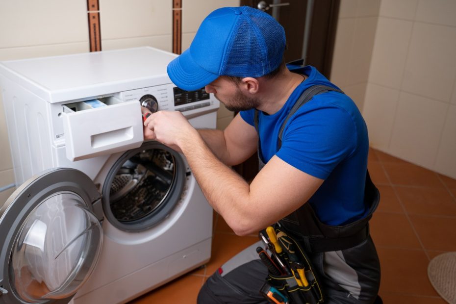 En man reparerar en tvättmaskin.