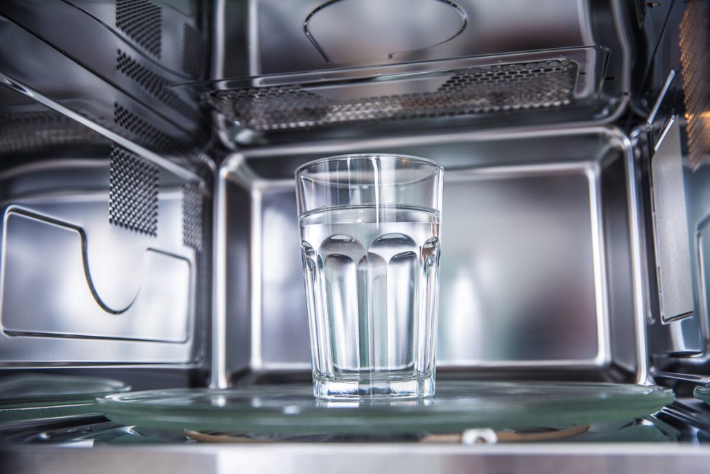En mikrovågsugn med ett glas vatten inuti.