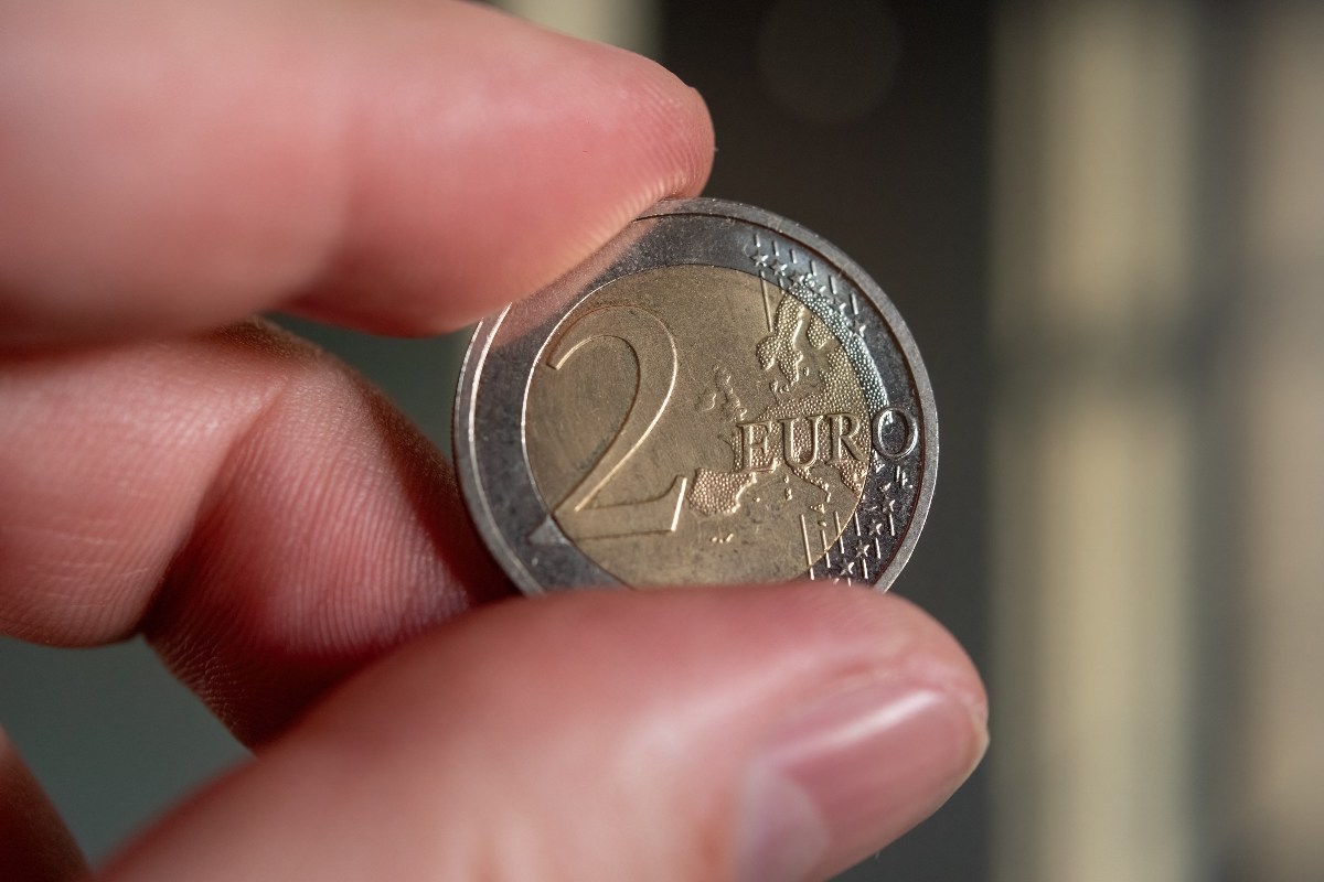 Een munt stuk van 2 euro in de hand.