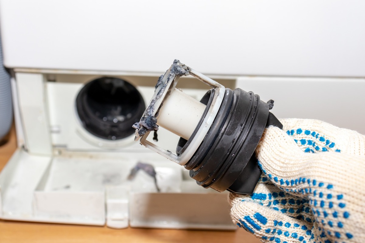 Mannen tog bort filtret från tvättmaskinen för att rengöra det.