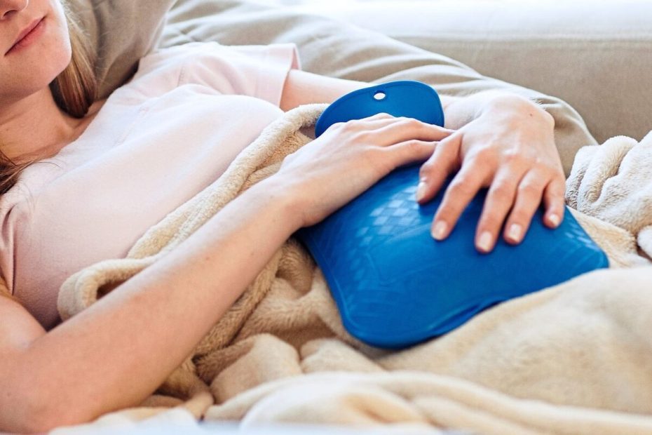 Flickan använder en varmvattenflaska för att värma sig.