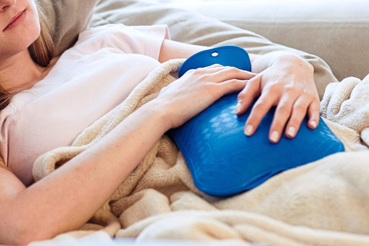 Flickan använder en varmvattenflaska för att värma sig.