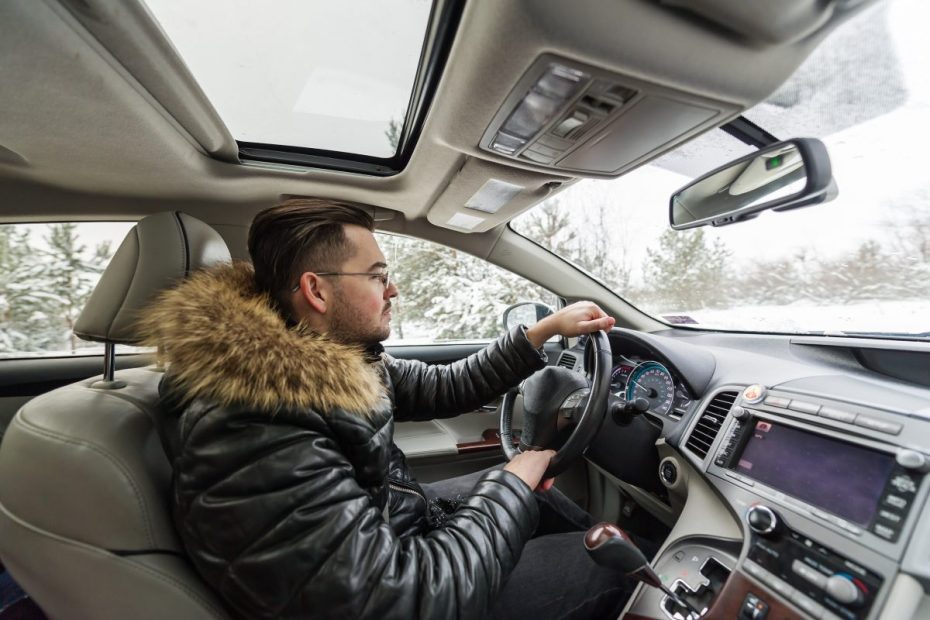 En man bakom ratten i vinterkläder.