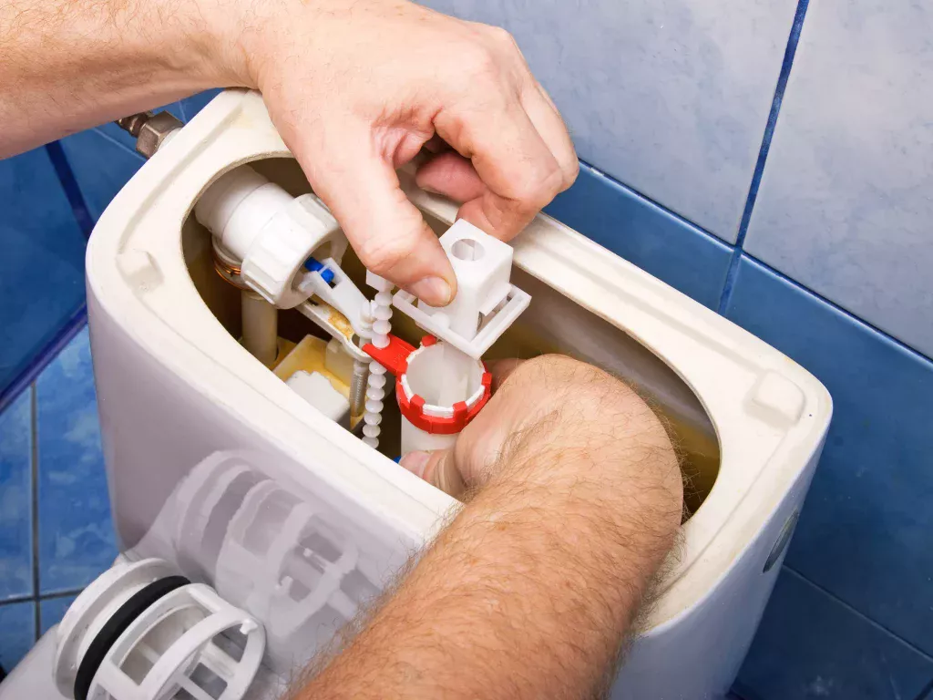 En man reparerar en toalettspolning med egna händer.