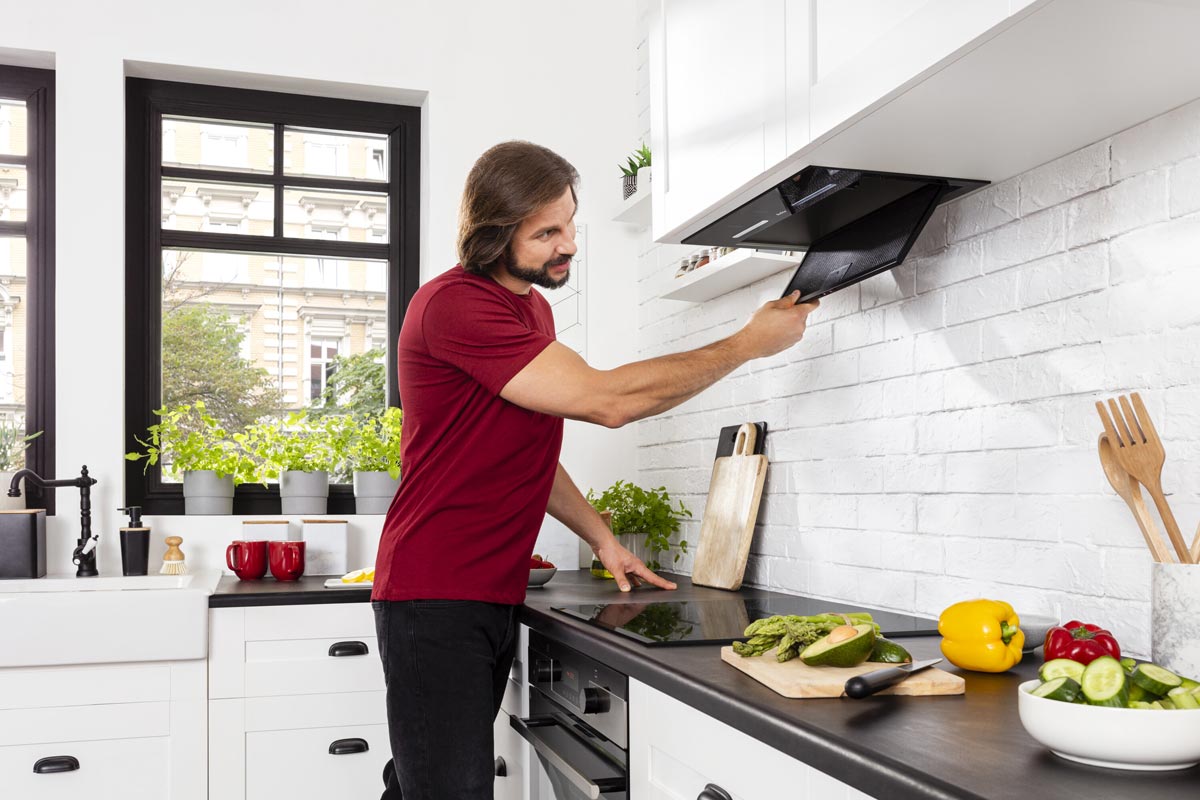 En man i köket inspekterar köksfläkten.