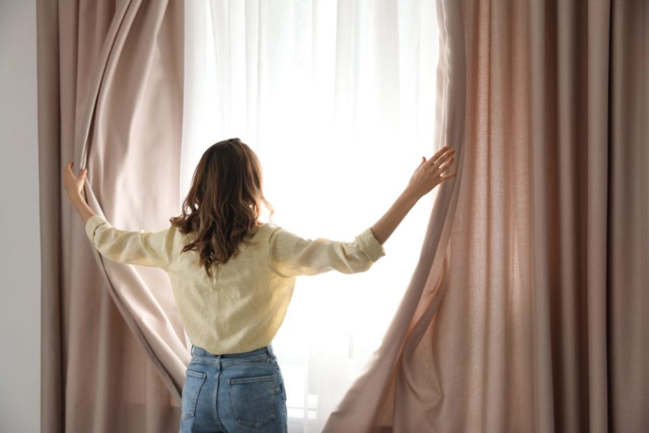 Flickan drar undan gardiner.