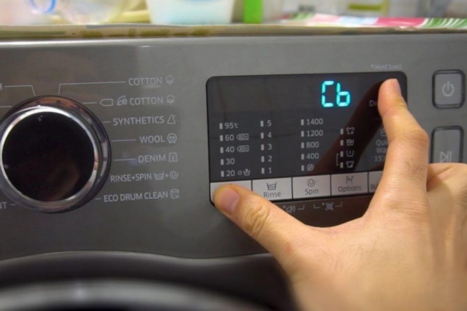 En person ställer in tvättmaskinen för att tvätten sina kläder.