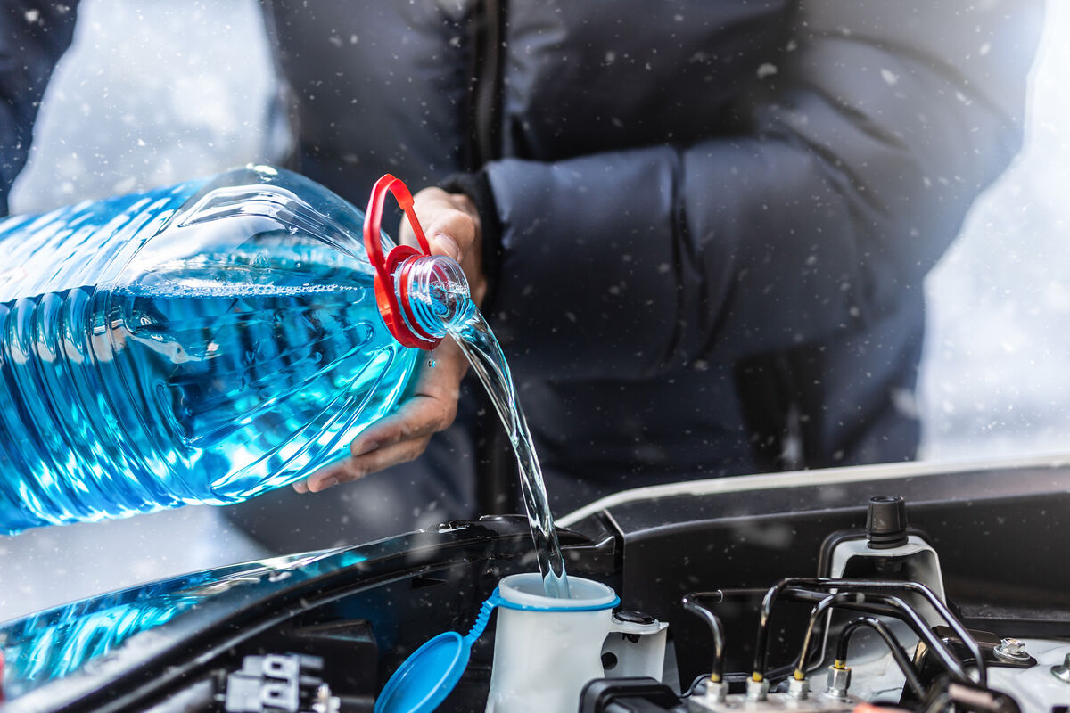 En man häller på spola rvätska.