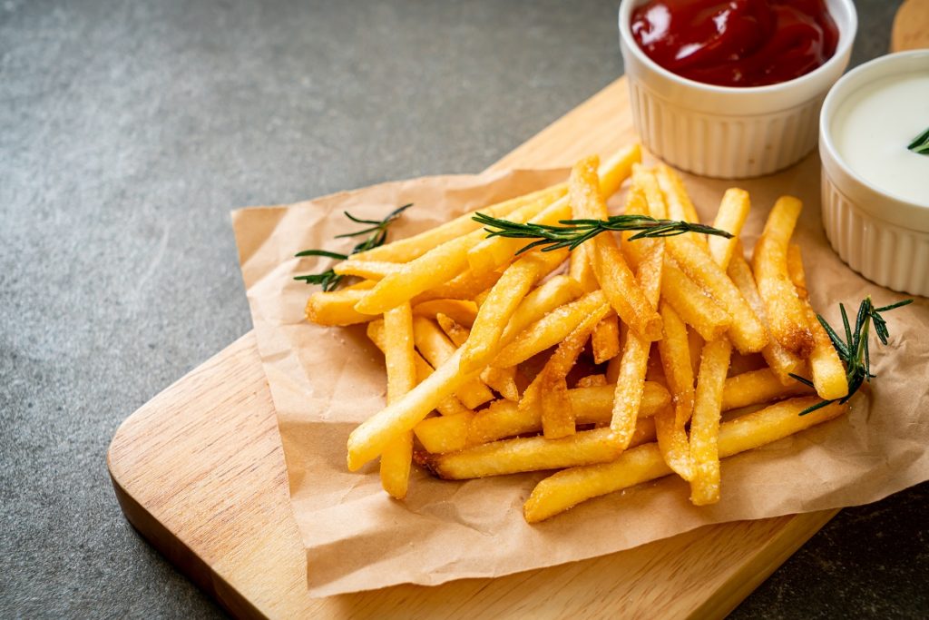 Färdiga pommes frites med ketchup och gräddfil.