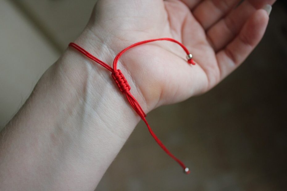 Mannen bär ett rött band på handleden.