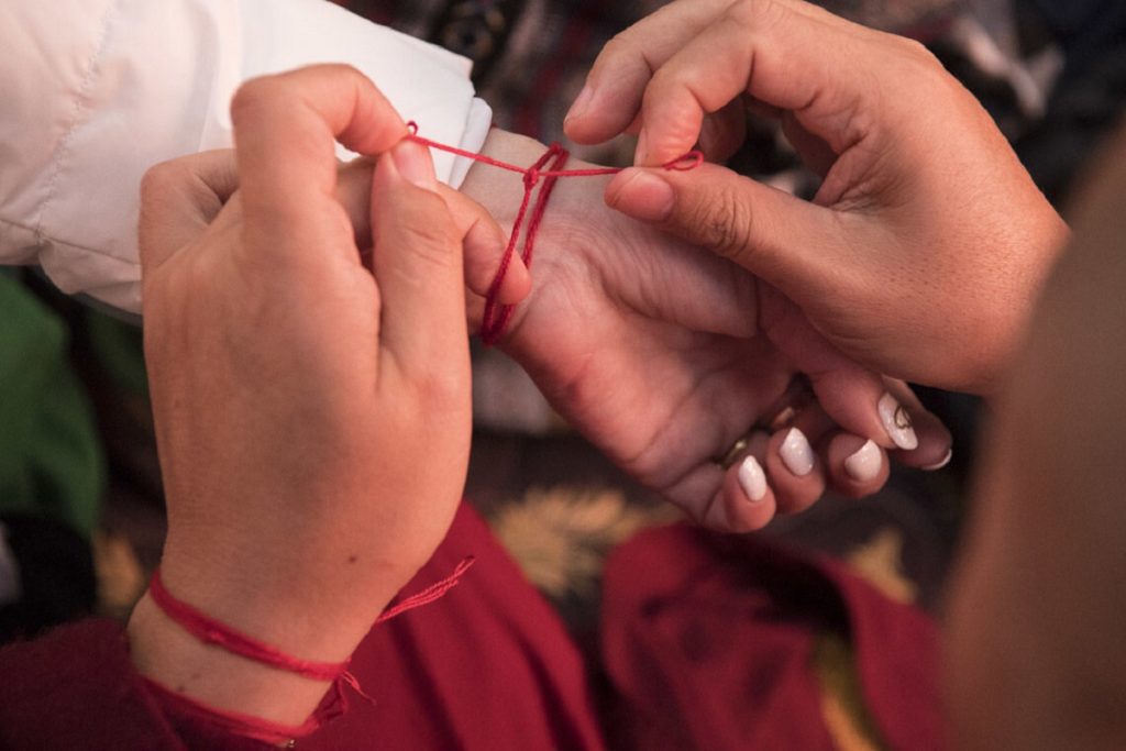 En man sätter ett rött band på handleden.