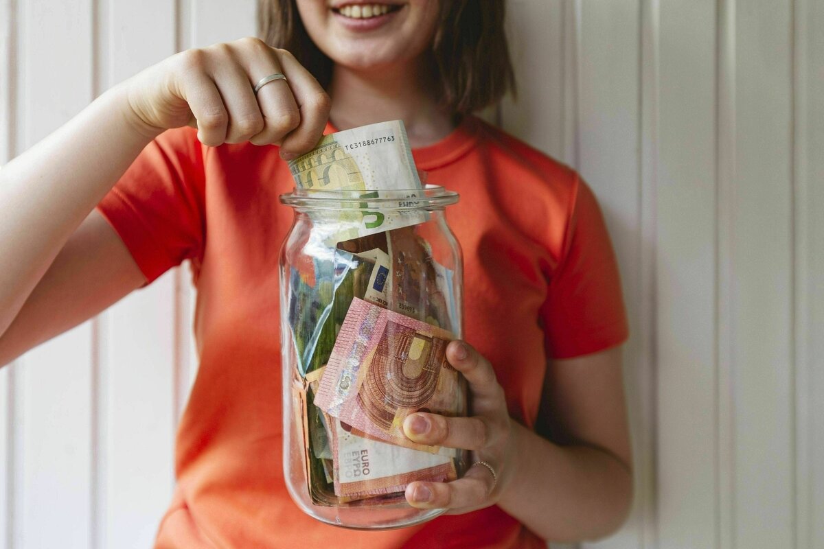 Flickan håller en burk med fickpengar i handen.