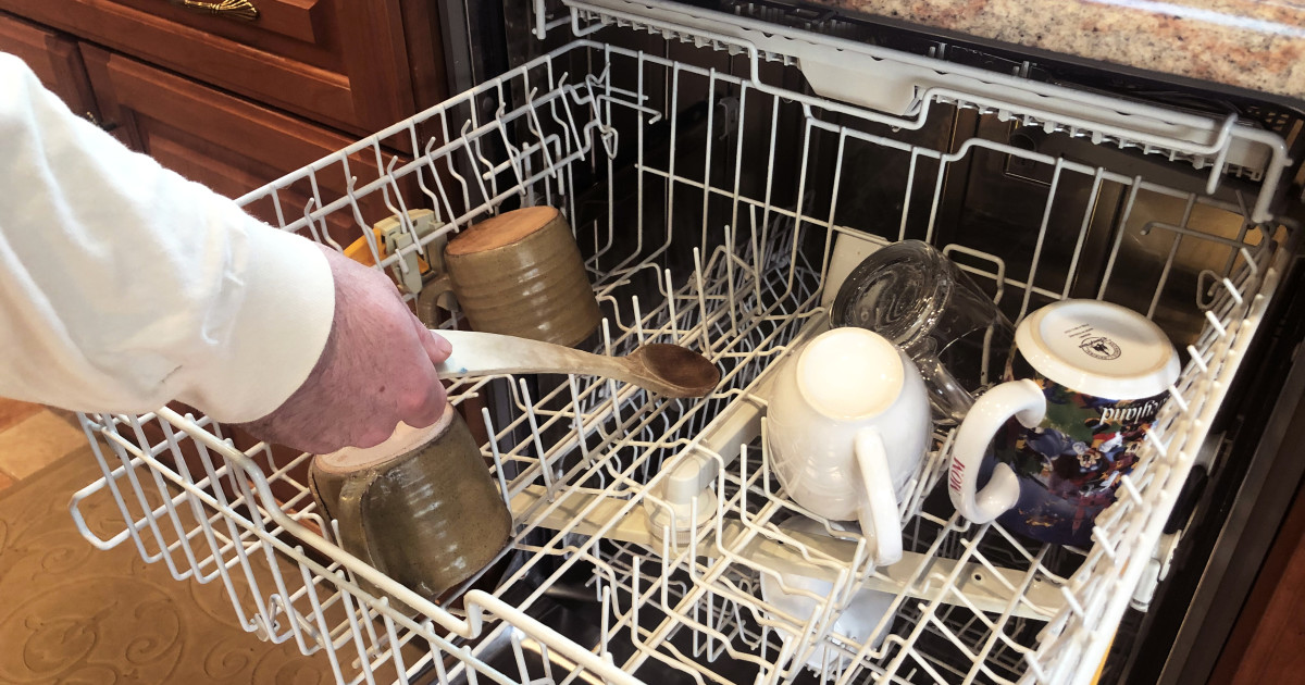 En person använder en träsked i diskmaskinen.