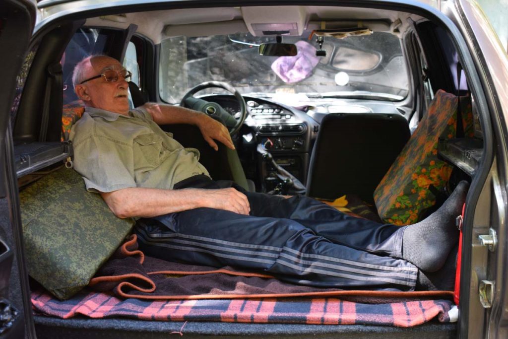 En äldre man sover i sin bil.