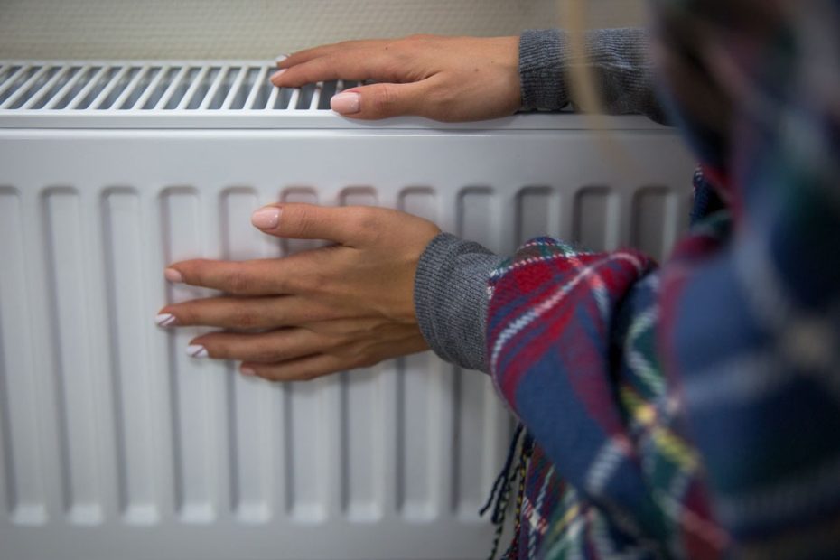 Flickan värmer sig vid Radiator.