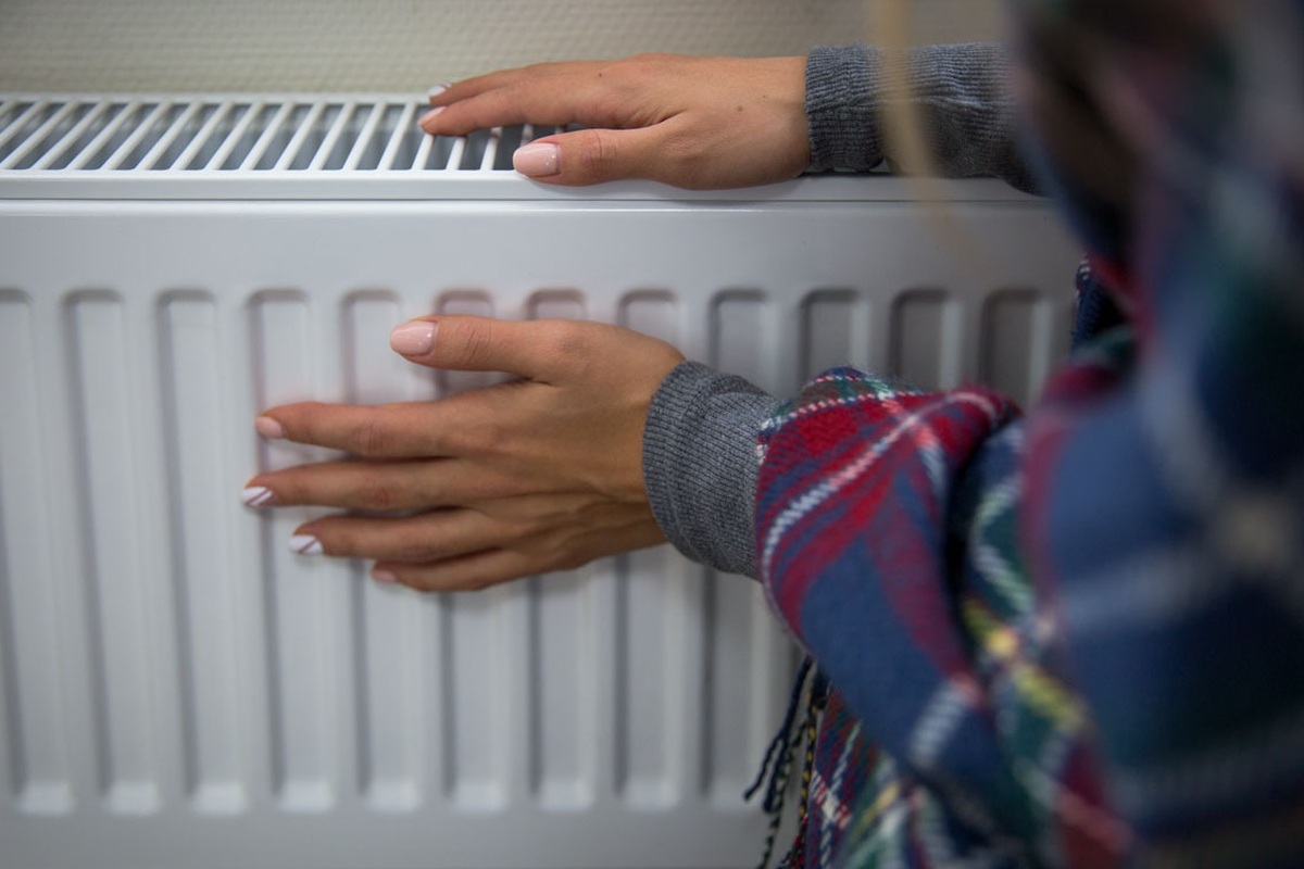 Flickan värmer sig vid Radiator.