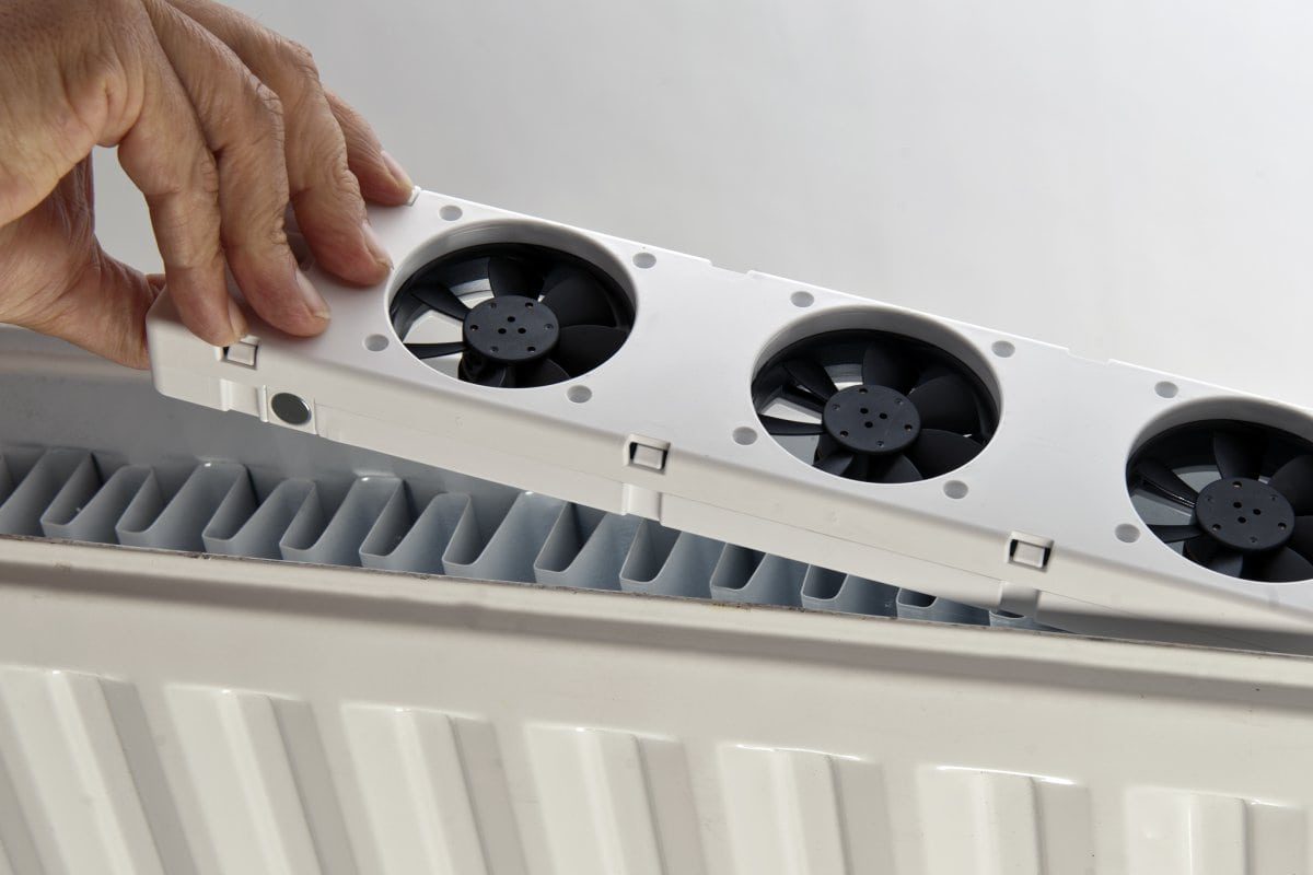 En man justerar en fläkt på en radiator.