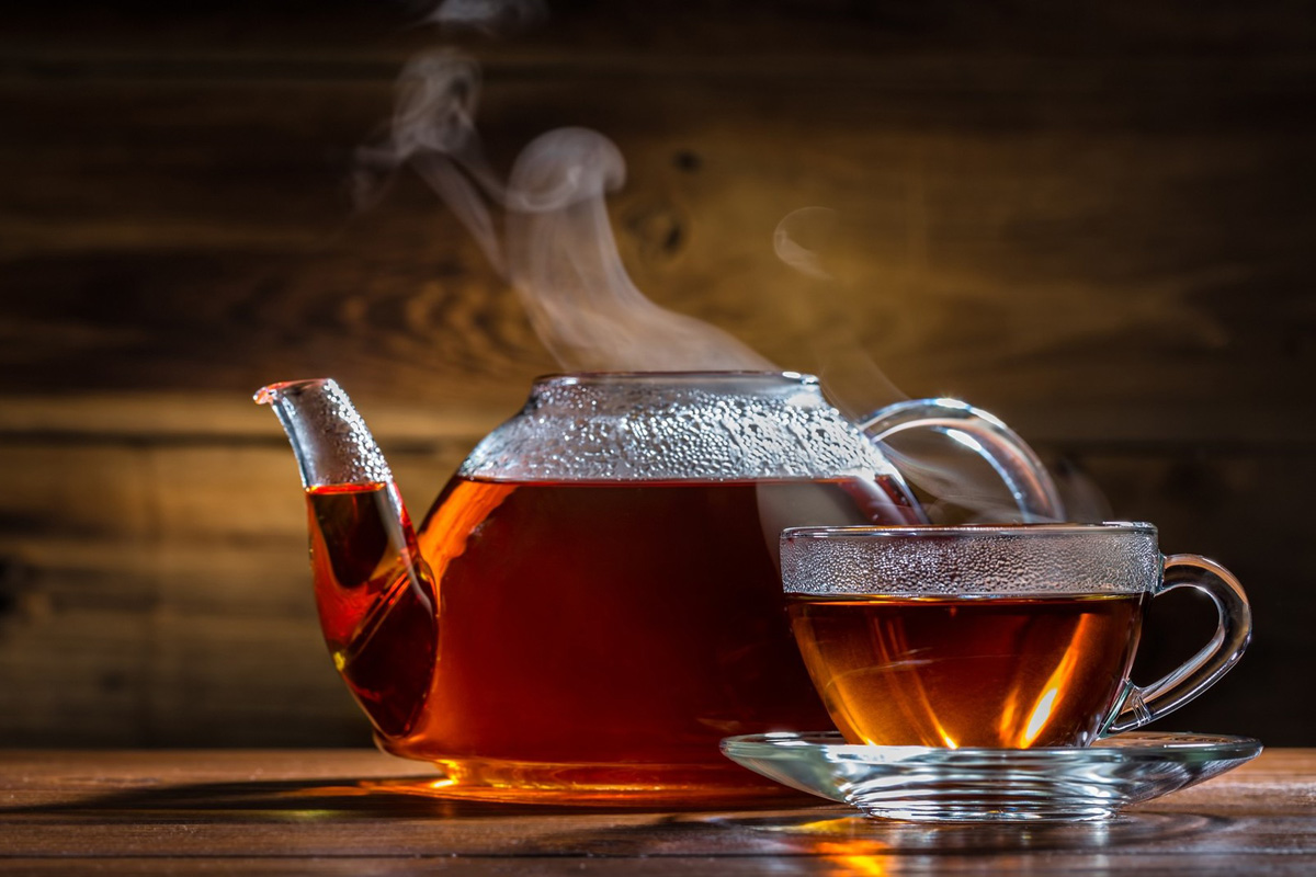 En person häller te i en kopp för att dricka senare.