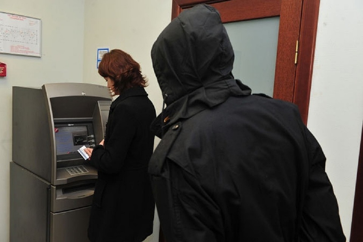 En bedragare försöker stjäla ett kort vid en bankomat.