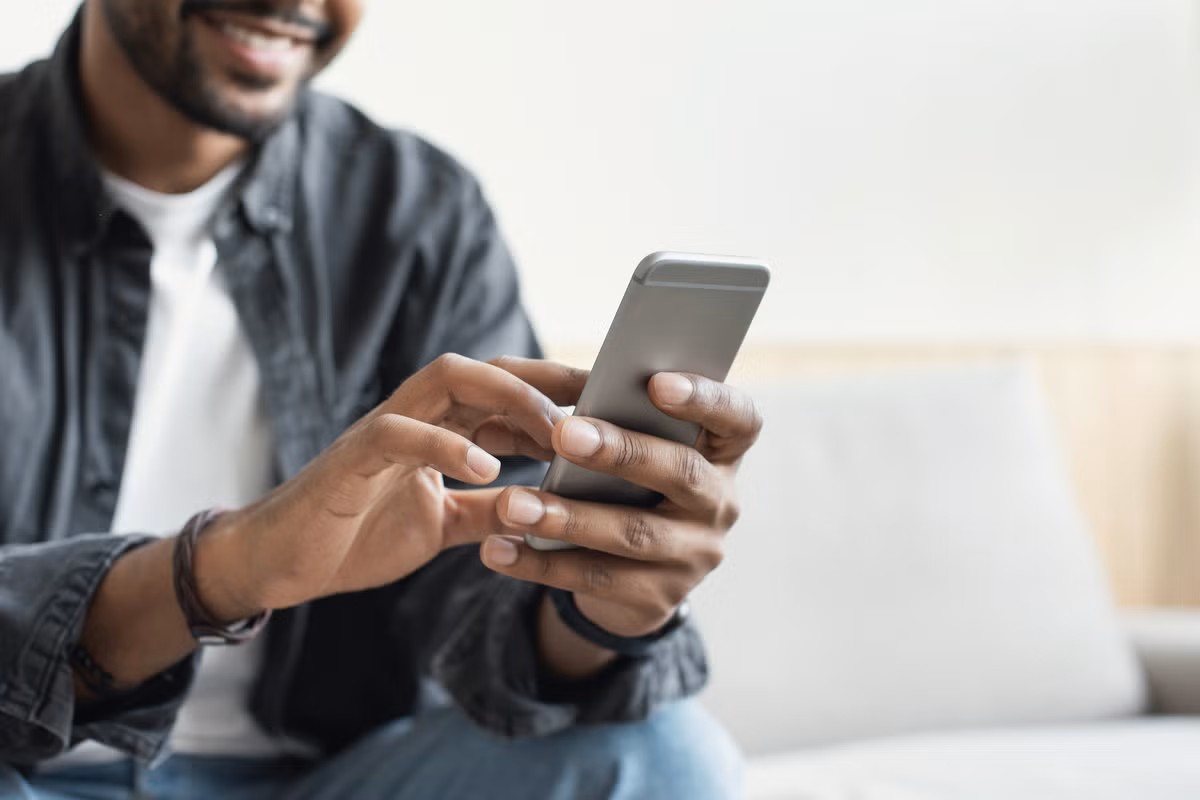 En man använder en smartphone i sina händer.