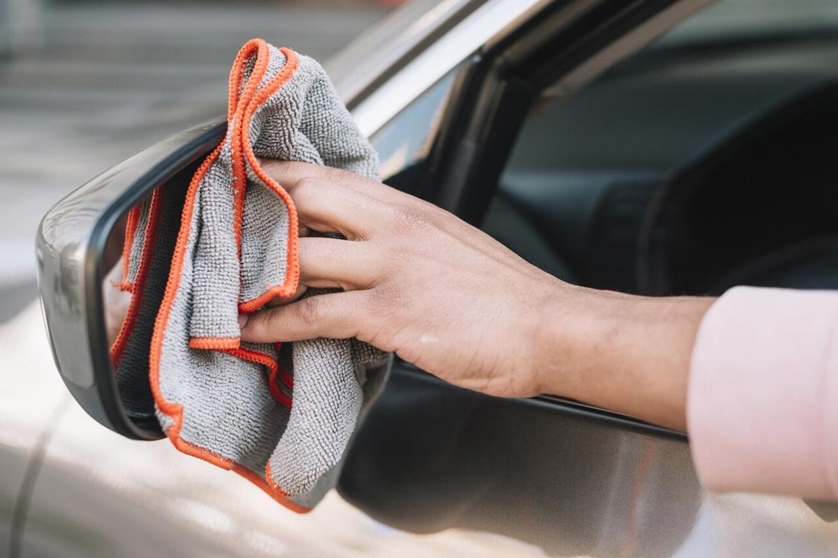 En man rengör backspeglarna.