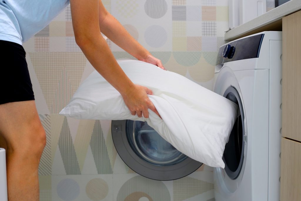 En person vill tvätta kuddar i tvättmaskinen.