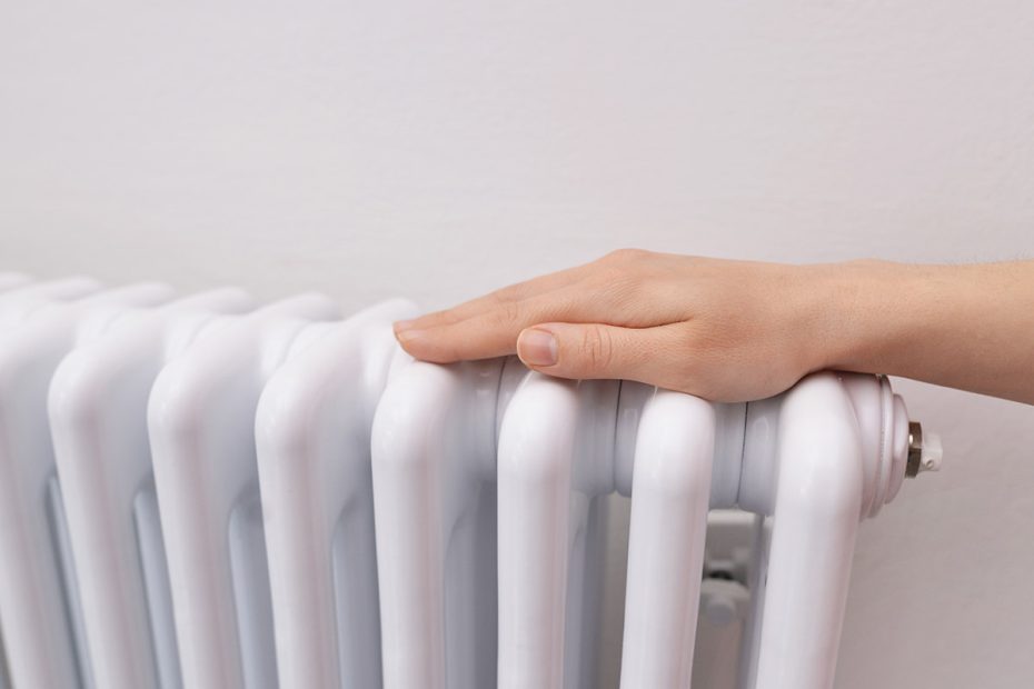 En person håller händerna på en radiator för att värme sig.