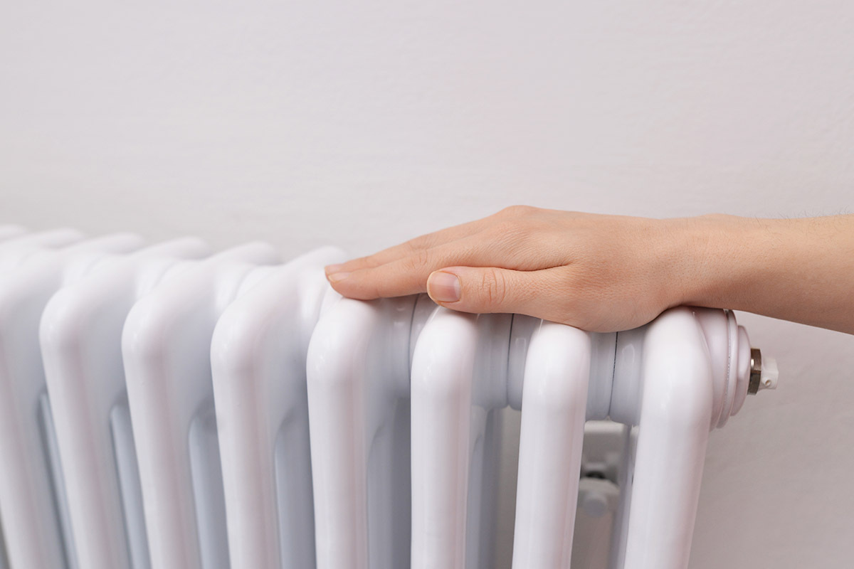 En person håller händerna på en radiator för att värme sig.