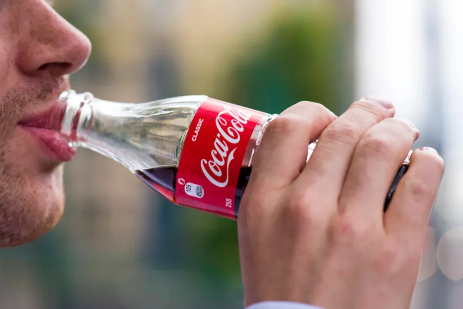 En man dricker Coca-Cola.