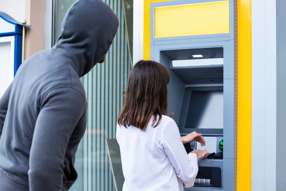 En bedragare observerar en person vid en bankomat.